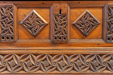 detail of the lock of an old wooden trunk with decorations in relief carved into the wood