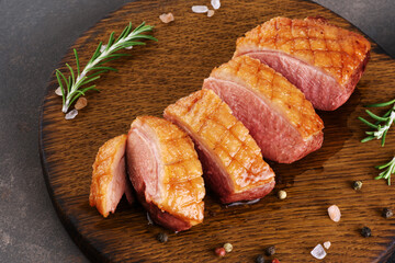 Roasted duck breast sliced on a cutting board.