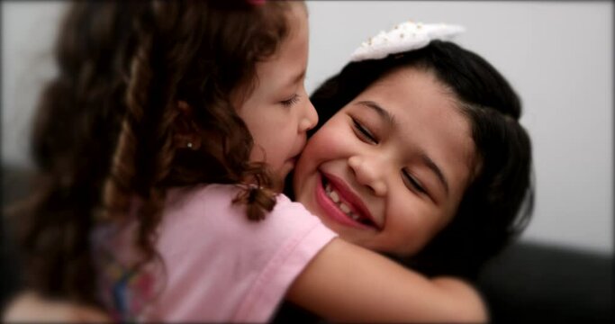 Cute mix race little sisters kissing each other. Children siblings love and affection