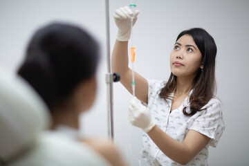 Close up of nurse or doctor preparing and adjusting infusion or chemotherapy drip for the patient in hospital or beauty salon. Healthcare, wellness and medicine concept