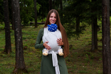 Pocket Wrap Cross Carry. Young mother with a baby in a wrap.
