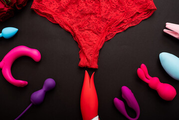 Top view of women's lace panties red roses and different sex toys. Collection of multicolored...