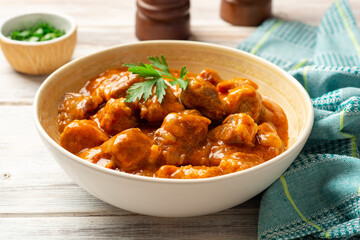 Meat stew in bowl on rustic wooden background