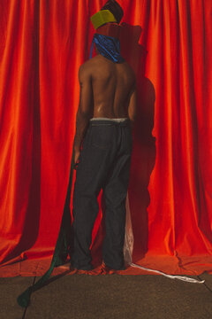Black Man Standing In Front Of Orange Backdrop Wearing Hats And Du Rags 