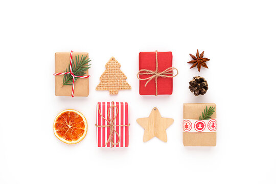 Christmas composition. Xmas flat lay craft red gifts, fir tree branch, dry sliced orange, star anise, pine cone, wooden stars, christmas tree and ribbon on white background.