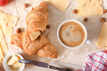 Breakfast with coffee and fresh croissants on light wooden background