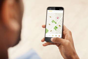 Black Man Booking Taxi Via Phone Using Application Indoors, Cropped