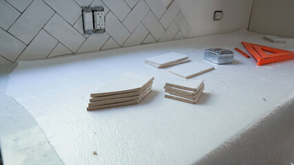 DIY home improvement project - installing white tile for a kitchen backsplash.