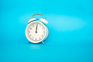 White alarm clock on a blue background. Free space for an inscription. Time concept