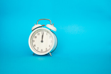 White alarm clock on a blue background. Free space for an inscription. Time concept