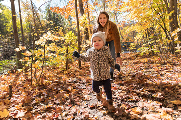 Little girl and her mother playing in the autumn park