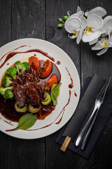 Grilled veal with sauce on a dark table
