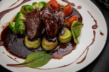Grilled veal with sauce on a dark table
