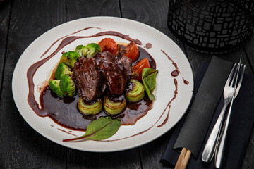 Grilled veal with sauce on a dark table
