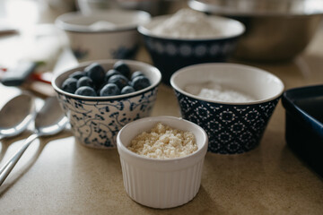 A close photo of blueberries, wheat flour, almond flour, sugar, powdered sugar which are preparing for cooking in the kitchen.