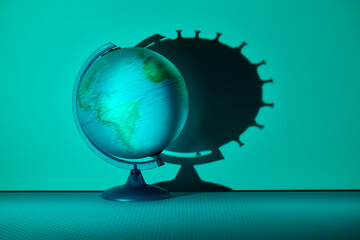 Spinning globe casting coronavirus biological cell shadow on wall