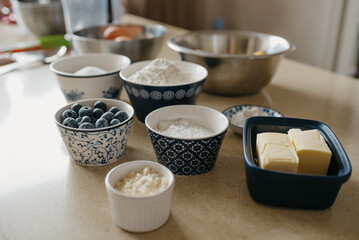 Wheat flour, almond flour, sugar, powdered sugar, blueberries, two pieces of butter, starch, eggs, lemons are preparing for the lemon meringue tart in the kitchen.