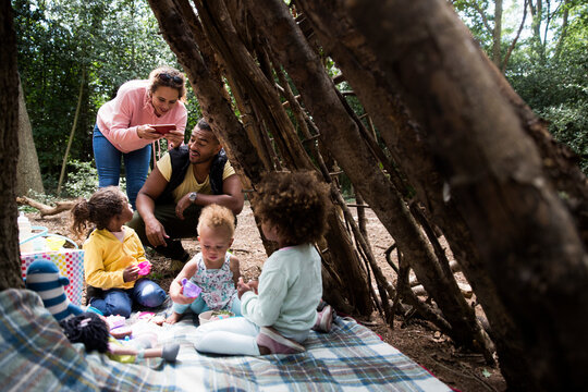 Happy family playing tea party in tree fort in woods