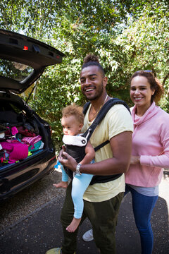 Portrait happy parents with toddler daughter outside car