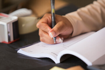 Close up female shop owner filling out receipt ledger