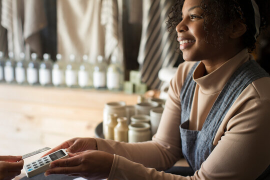 Friendly female shop owner holding credit card reader for customer