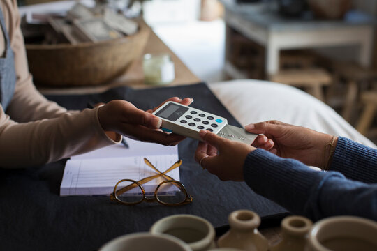 Close up shop owner holding credit card reader for customer at counter