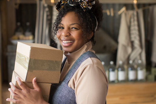 Portrait happy confident female shop owner with cardboard boxes