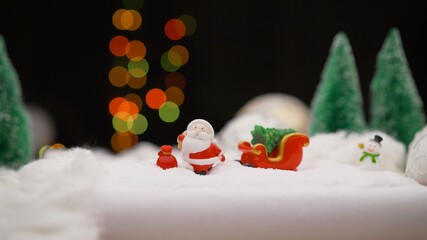 Toy Santa Claus on the background of light bulbs. Christmas background Santa Claus with a gift. Christmas toy on garland background