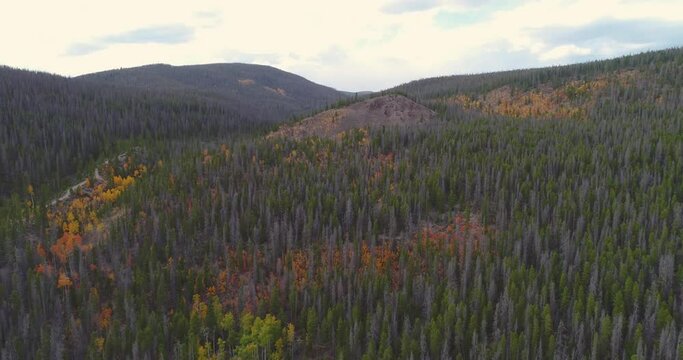 Aerial of Colorado mountain range during fall with spots of aspens 
