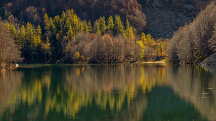 Reflections of autumn foliage in the still water of Lake Santo Modenese, Emilia Romagna, Italy