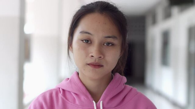 A female teenage Asian high school student girl in a pink sweater shook her head and refused dissatisfied.