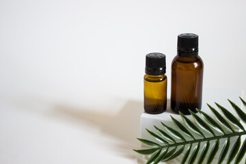 glass brown jars with plant stracts and oils on a light white background. For cosmetics or cosmetology background. stand for advertising beauty products. Plants decor eucalyptus, fern, spruce