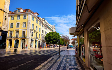 Lisbon Portugal. Empty wide street with storefront shop and yellow building. Scenic cityscape with blue sky.