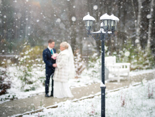 Fototapeta premium Wedding couple at a winter snow wedding. A blurry silhouette with unrecognizable persons.