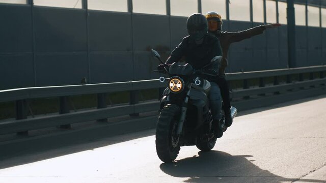 Close-up Happy Bikers in Helmets Riding on Motorcycle. Portrait of Caucasian Couple Man and Woman Driving Motorbike on Sunny Day Outdoors. Funny Carefree Girl Feels a Sense of Freedom. Slow mo Shot 4k