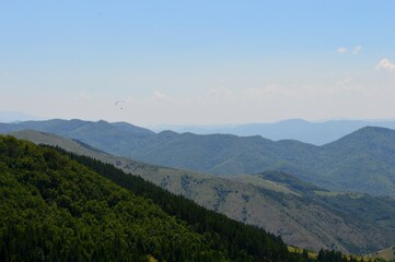 a paraglider flies over mountain peaks