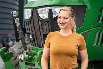 Agrarberufe -  Symbolfoto,  junge  und selbstbewußte Landwirtin steht an einem Traktor.