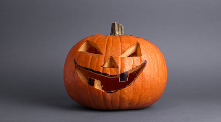 Halloween pumpkin or jack-o-lantern with glowing eyes on a gray background. Halloween pumpkin with copyspace on gray background. 