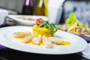 Fillet of white fish in sauce on a plate with garnish and herbs.