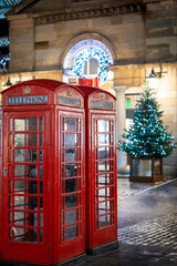 Red telephone booths in front of Christmas decorations lights in the Covent Garden district, London, United Kingdom