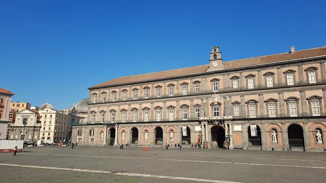 Naples, Italy. October 22th, 2020. People Strolling by the main external facade of the Royal Palace of Naples in Piazza del Plebiscito, with blue sky on a warm and sunny October day.