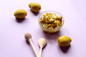 Mature Japanese quince fruit with wooden spoons on a purple background, side view-the concept of using vitamin fruits in cooking