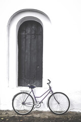Fototapeta na wymiar The bike is at a beautiful old door. The bike stands near a white wall. Bike and door