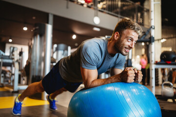Portrait of fit handsome man workout on a fitness machine at gym