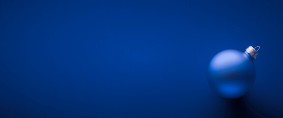 Light blue round matt Christmas ball. Christmas ornament standing on blue background.