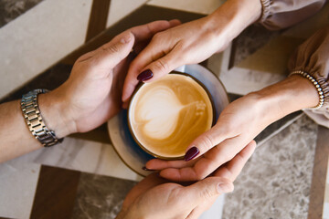 Fototapeta na wymiar Man and woman holding hands on a coffee cup. Love concept.