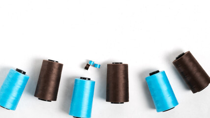 Blue and brown spools of thread. Sewing accessories on a white background. Top view, flatlay, horizontal orientation.