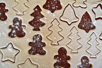Christmas cookie dough stretched and cut with molds in the shape of a gingerbread man, stars and trees