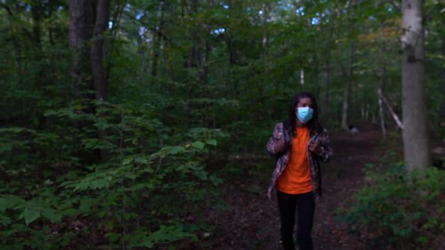 Black Man Wearing Coronavirus Prevention Mask Walks Forward in Forest