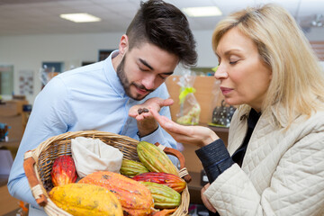 grocer and customer smelling exotic fruits